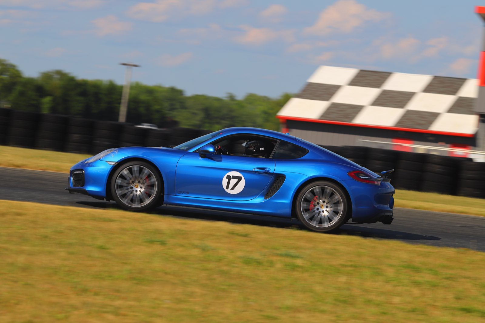 The number 17 Cayman GTS on the front straight at NJMP Lightning, checkered start tower behind