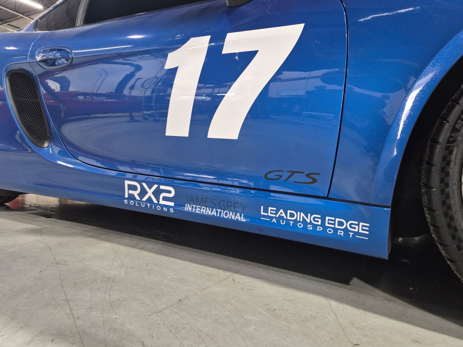 Blue Porsche Cayman GTS with a white number 17 on the door and partner logos on the side skirt